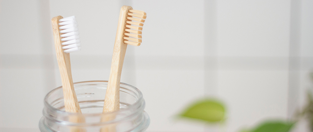 Two wooden toothbrushes in a glass pot