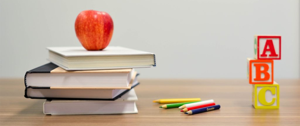 Apple on stack of books, crayons and ABC blocks